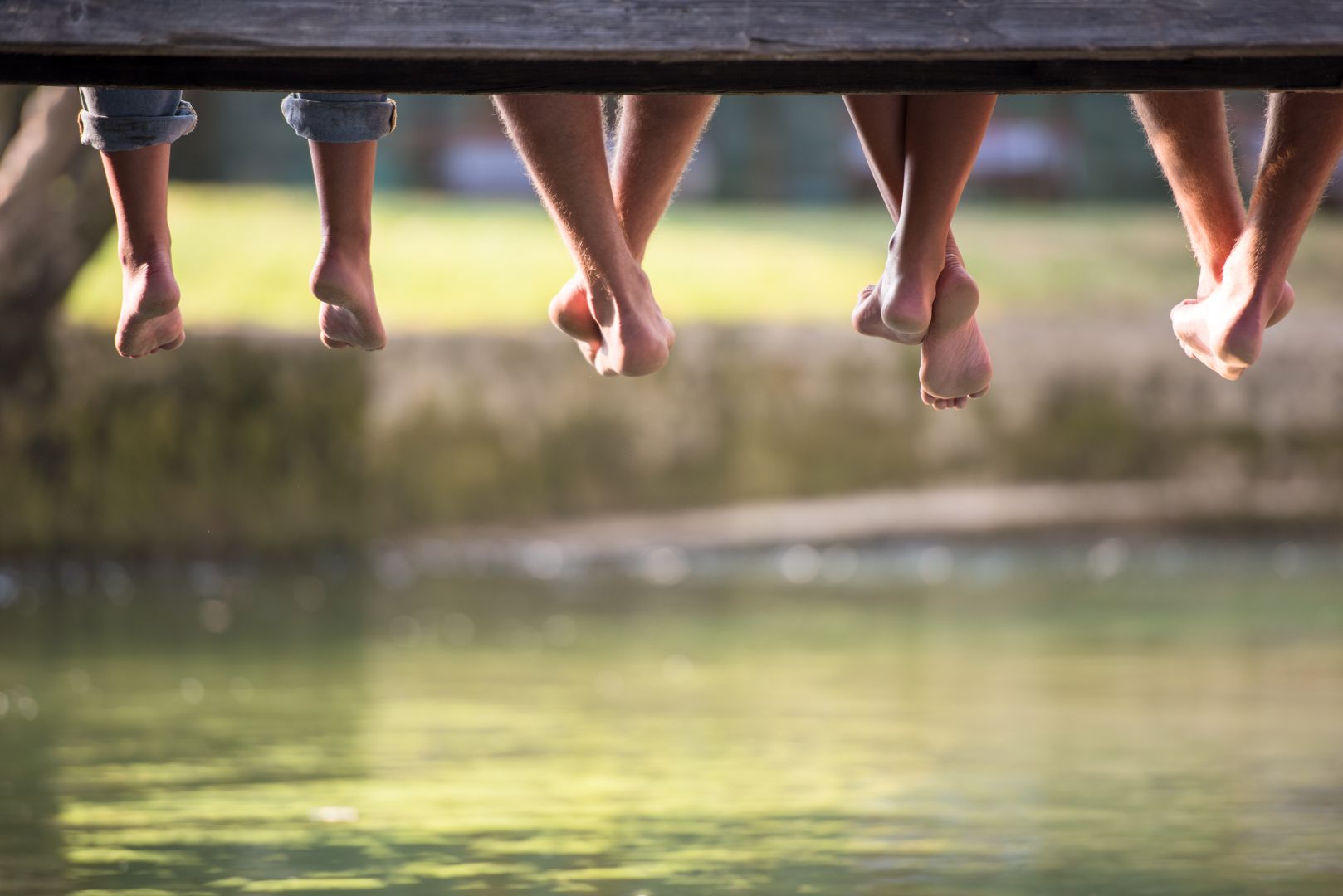group-people-sitting-wooden-bridge-river-with-focus-hanging-legs.jpg