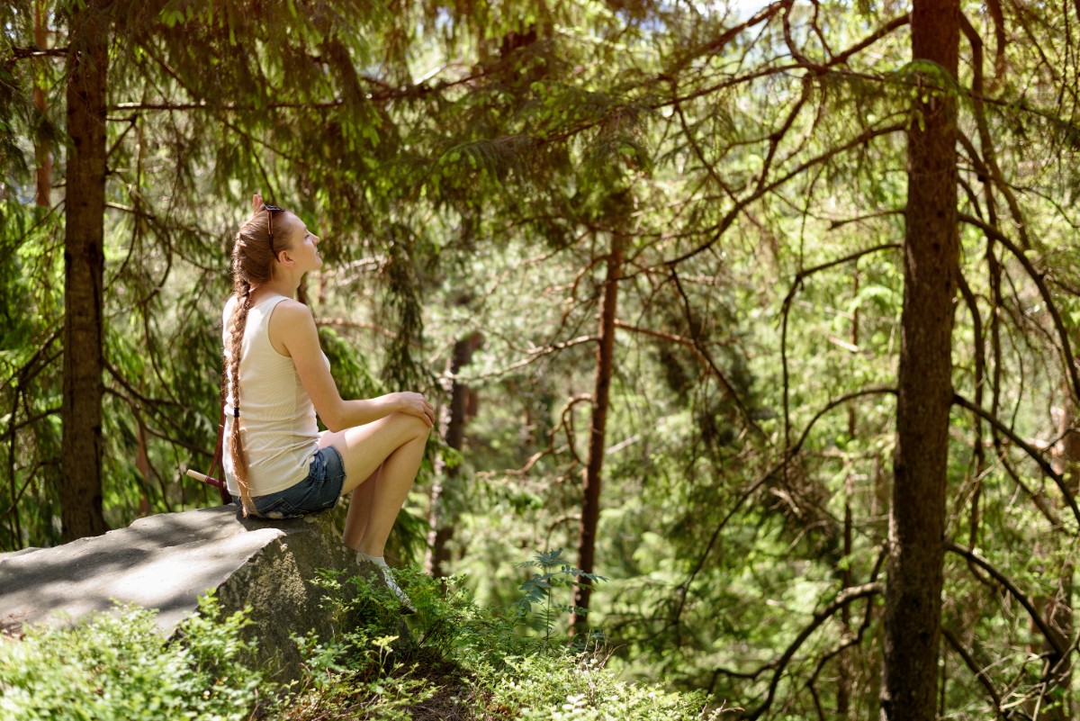 dreaming-beautiful-girl-sitting-stone-surrounded-by-coniferous-forest-sunny-day.jpg